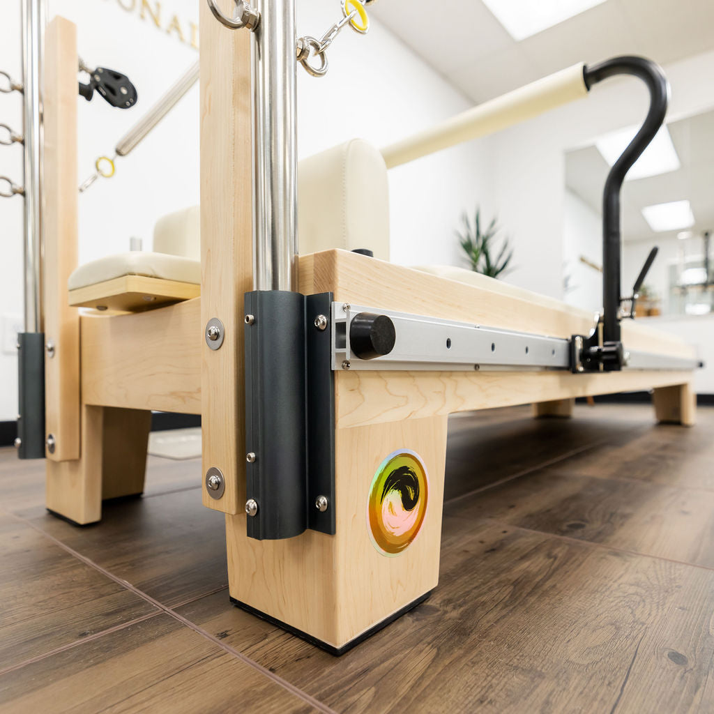 Pilates reformer with wooden frame and adjustable settings for versatile workouts.