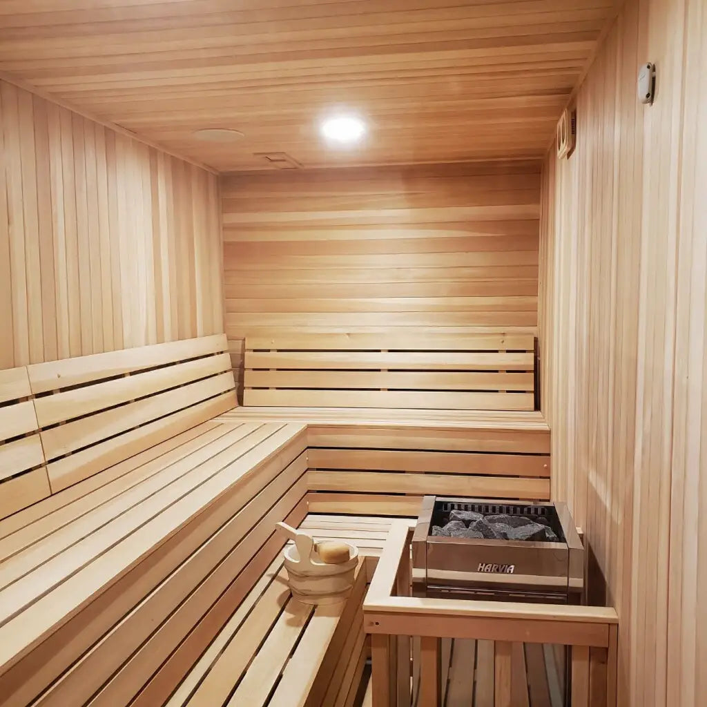 Wooden sauna interior featuring benches and a heater for relaxation.