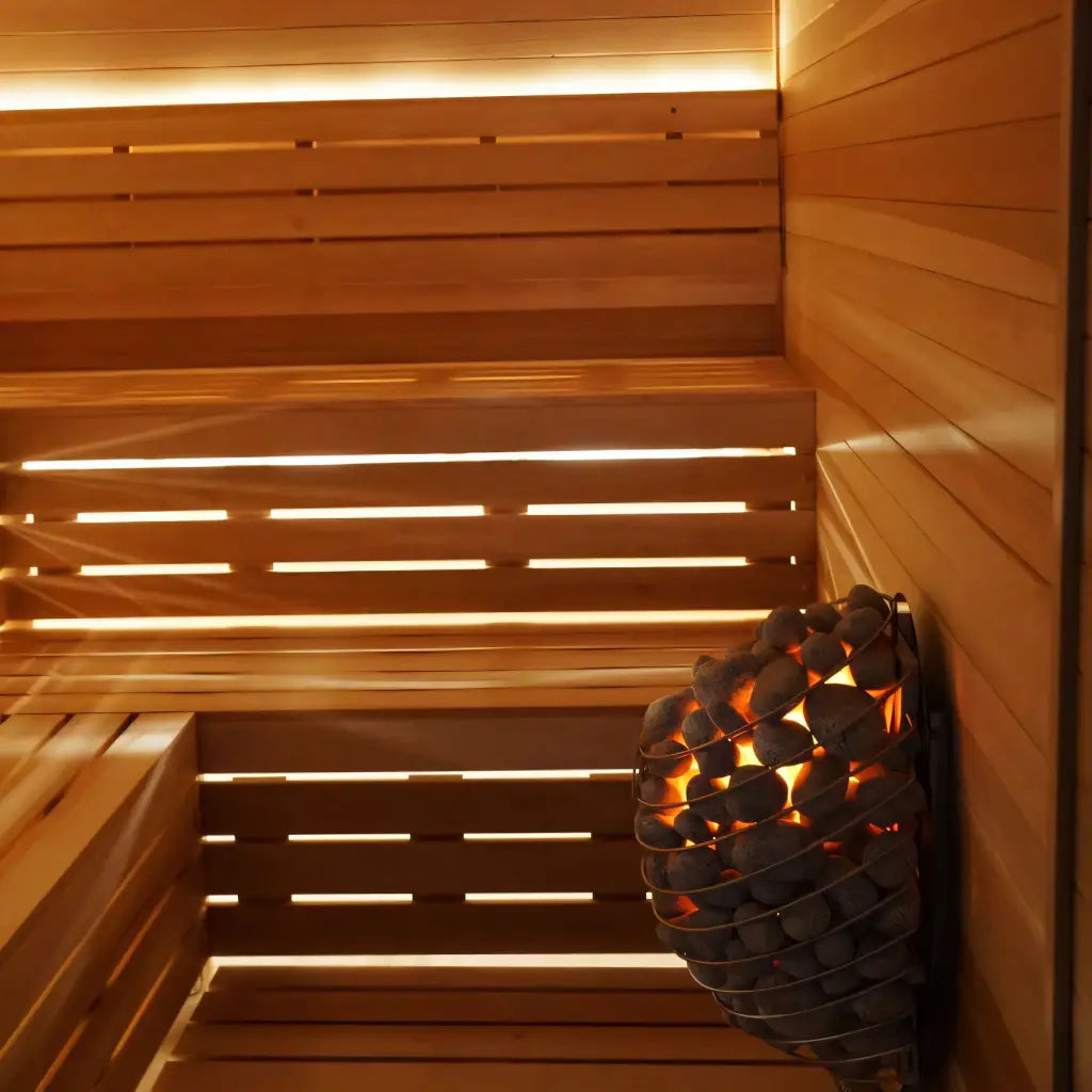 Wooden sauna interior featuring a stone heater and warm lighting.