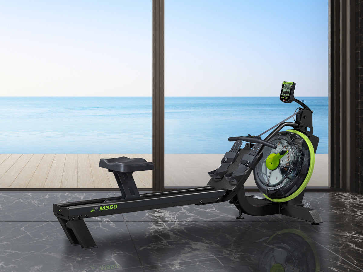 Maxo rowing machine with sleek design and green accents, positioned by a large window overlooking the sea.
