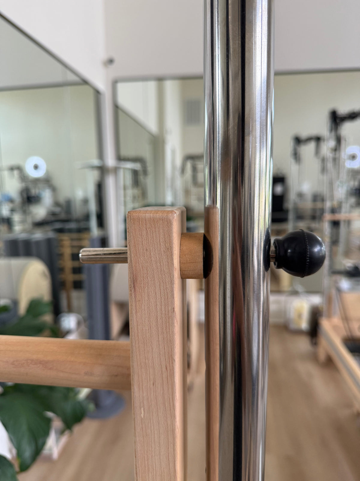 Wooden and chrome pole attachment for fitness equipment, showcasing sleek design and functionality.