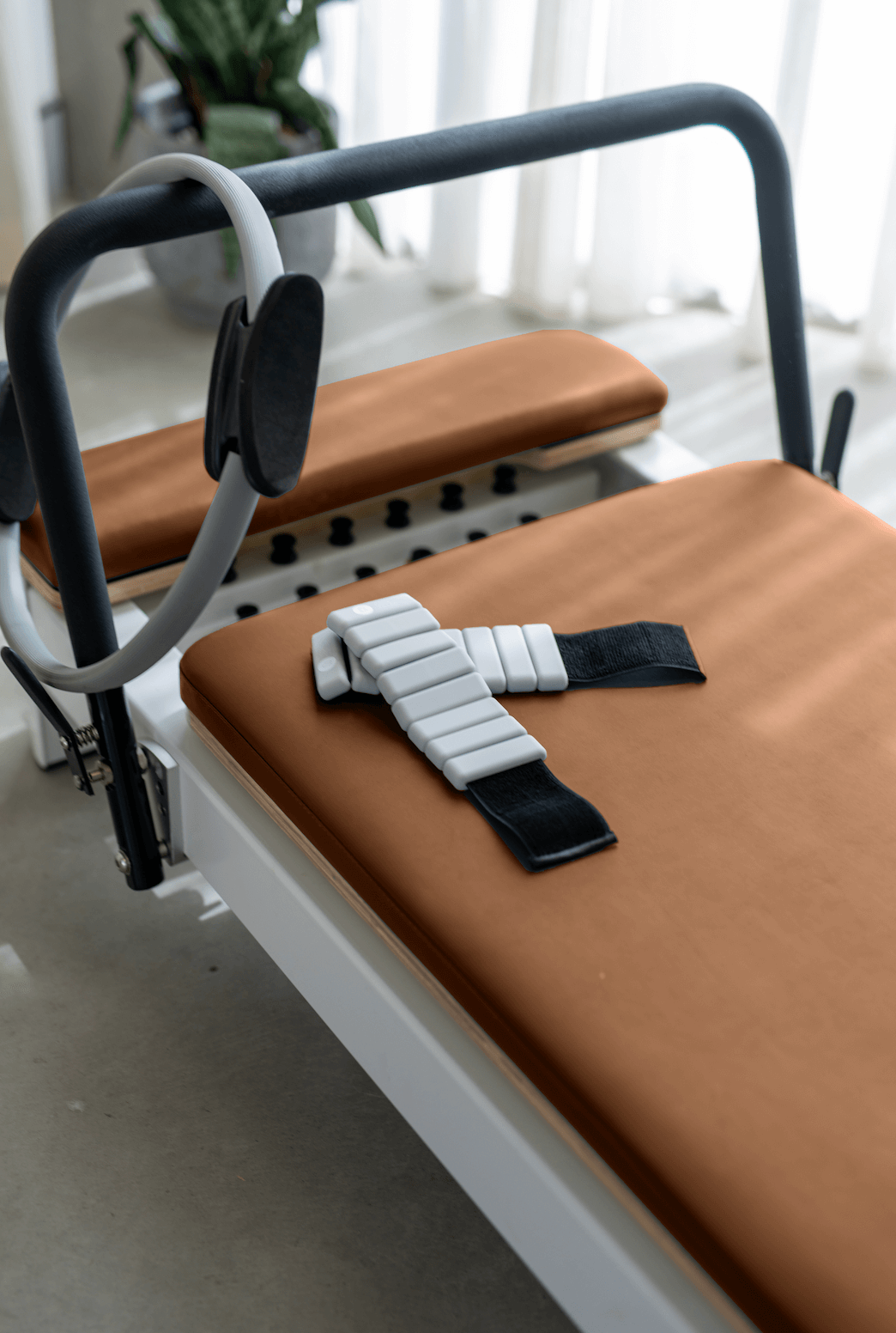 Reformer Pilates machine with orange padding and adjustable straps for workouts.