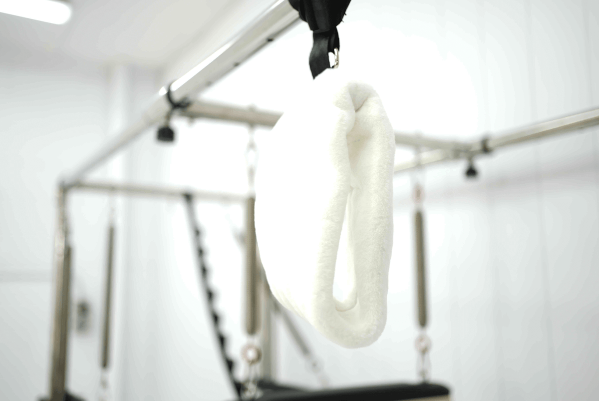 Gymnastic rings in white color hanging from a metal frame, ideal for strength training.