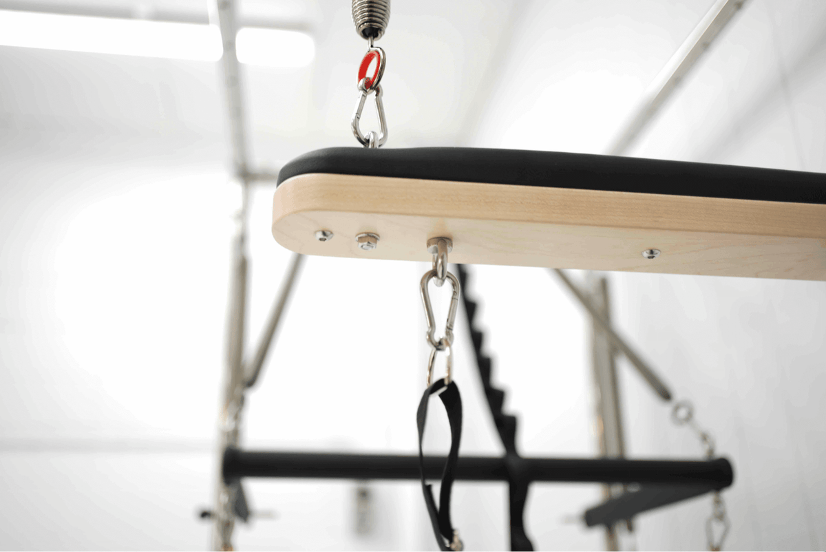 Wooden gym equipment with pulleys and straps for strength training.