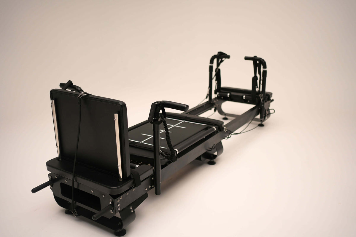 Pilates reformer machine with adjustable settings and black frame for versatile workouts.