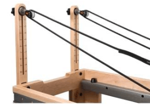Pilates reformer with adjustable straps and wooden frame for versatile workouts.