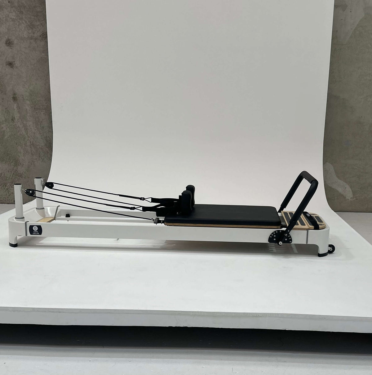 Pilates reformer machine with adjustable straps and padded platform for workouts.