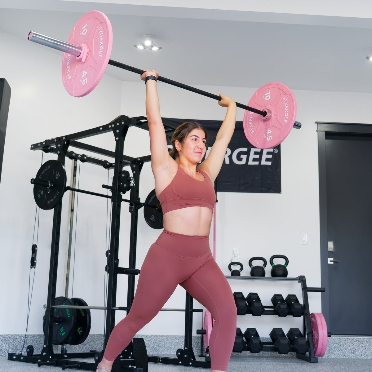 Pink Weight Barbell Set used by a woman in workout attire, showcasing strength training.