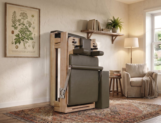 Wooden Pilates reformer with green upholstery, designed for home fitness.