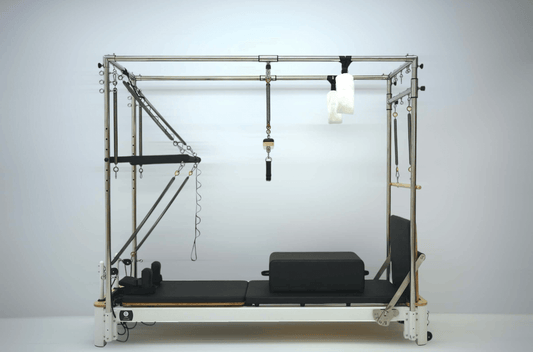 Pilates reformer machine with adjustable straps and padded bed for workouts.